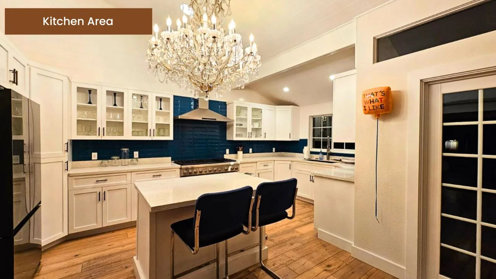 Kitchen with a large island, chandelier, and deep emerald tile backsplash