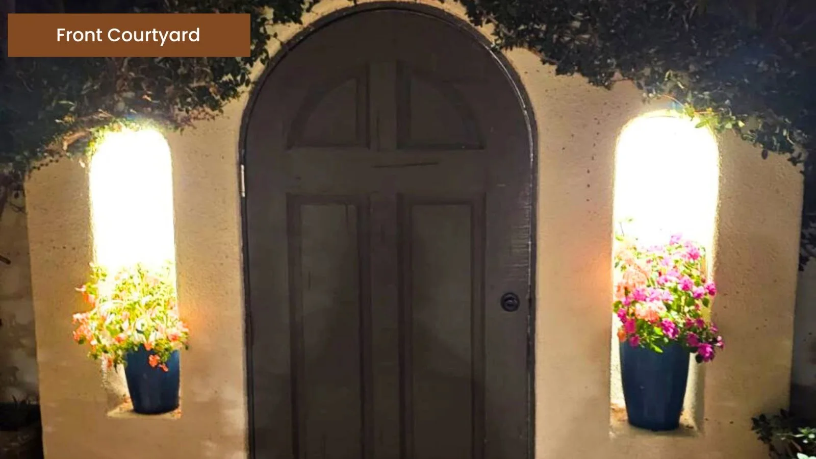 Arched front door framed by courtyard lanterns at dusk